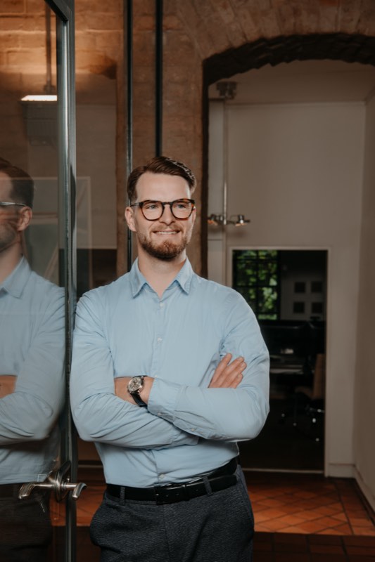 Businessporträt: Mann mit verschränkten Armen im Backstein-Büro